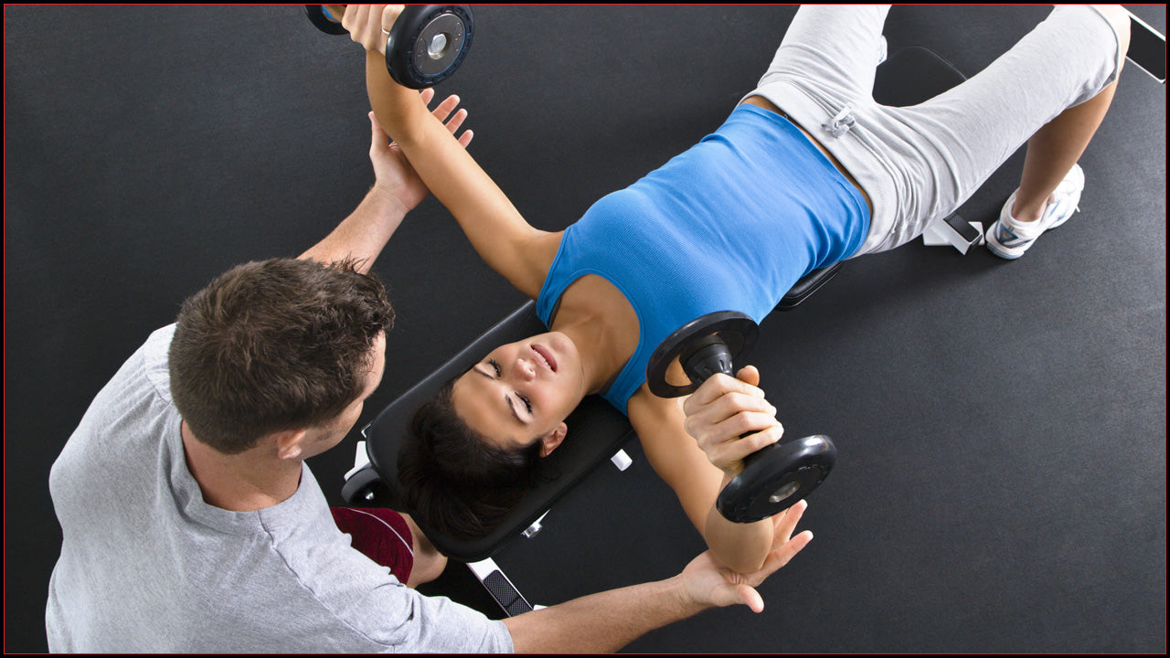 Woman on a weight bench lifting dumbbells.