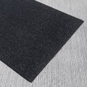 Black rubber gym mat on a textured gray surface