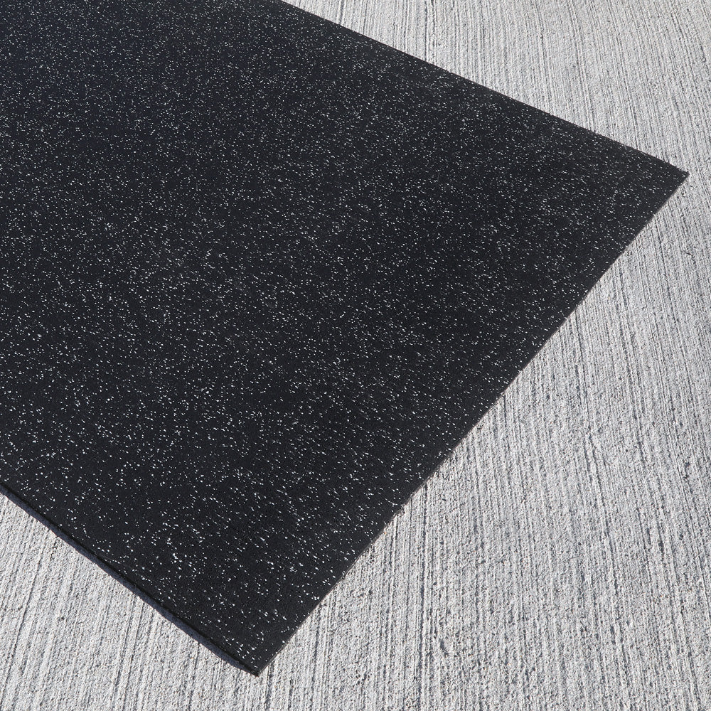 Black rubber gym mat on a textured gray surface