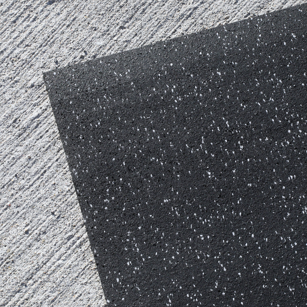 Close-up of a black recycled rubber fitness mat for weightlifting area against a light gray background
