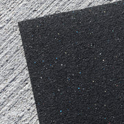 Close-up of heavy-duty rubber gym mat for weightlifting area on a textured gray surface.