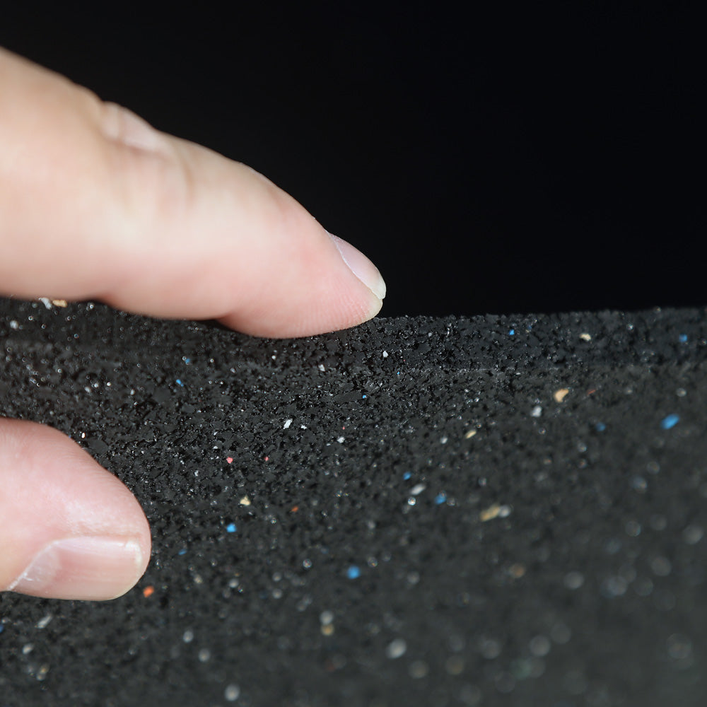 Close-up of a hand holding black rubber gym matt against a dark background