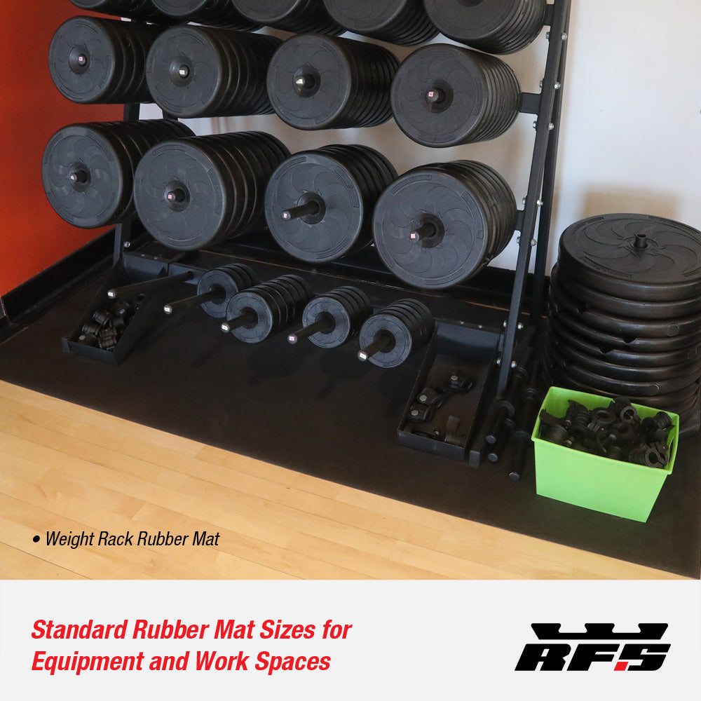 Stacked weight plates on a rack with a rubber mat under it in a gym setting.
