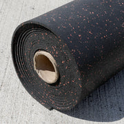 Roll of black rubber gym flooring with terra cotta specks on a concrete surface.