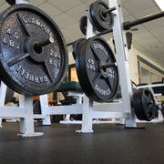 Barbell with weight plates on a rack in a gym setting over 8mm Rubber Roll flooring.