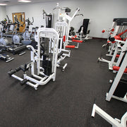Gym interior with various exercise machines on gray fleck rubber tiles.