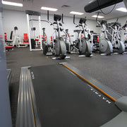 Gym interior with treadmills and stationary bikes on rubber gym tiles.