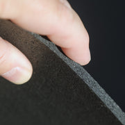 Hand holding a black recycled rubber fitness mat for weightlifting area