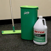 Green mop bucket and white bottle of Betco Best Scrub on a black floor.