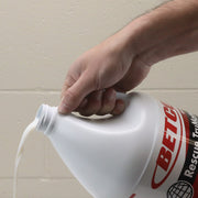 Hand pouring a gallon of Betco Rescue TruMatte into a container.
