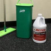 Green bucket, green mop, and white Betco bottle on a black surface.