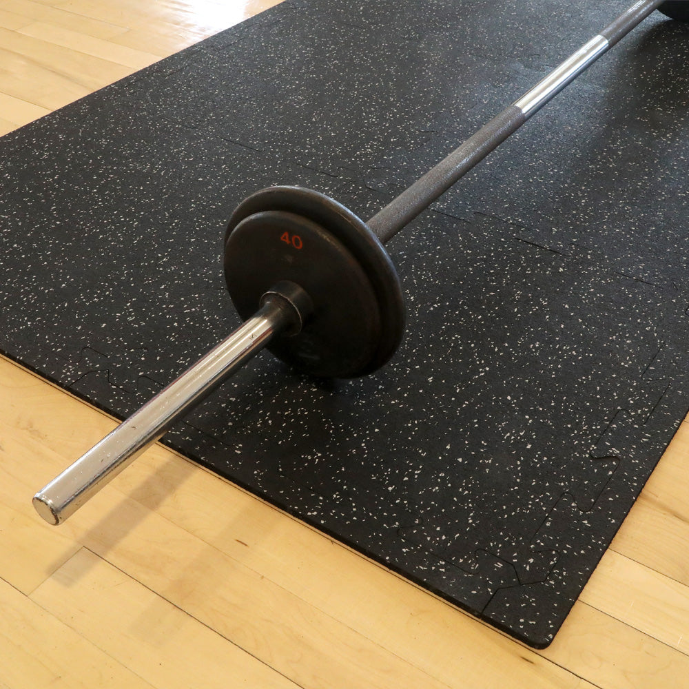Barbell on 6 rubber gym tiles that have been interlocked together to form a mat.