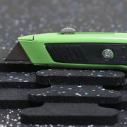 Green utility knife on a textured black surface