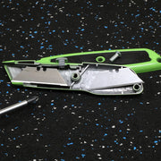 Disassembled green utility knife on a black speckled surface